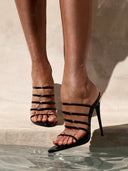 Model wearing the Kalós Slipper in Patent Black, close-up on foot and ankle